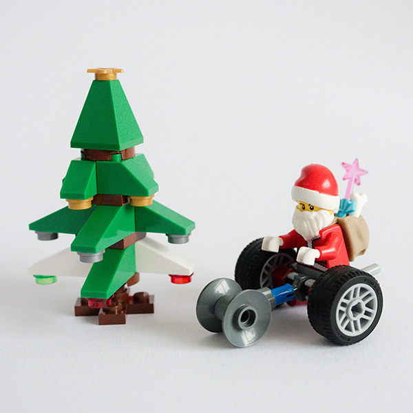 #ToyLikeMe makeover image showing Lego wheelchair mini-figure Santa with wheelchair next to Lego Christmas tree.