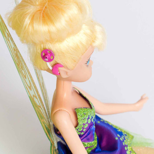 #ToyLikeMe makeover image of a Disney Tinkerbell doll with a model cochlear implant in hot pink.