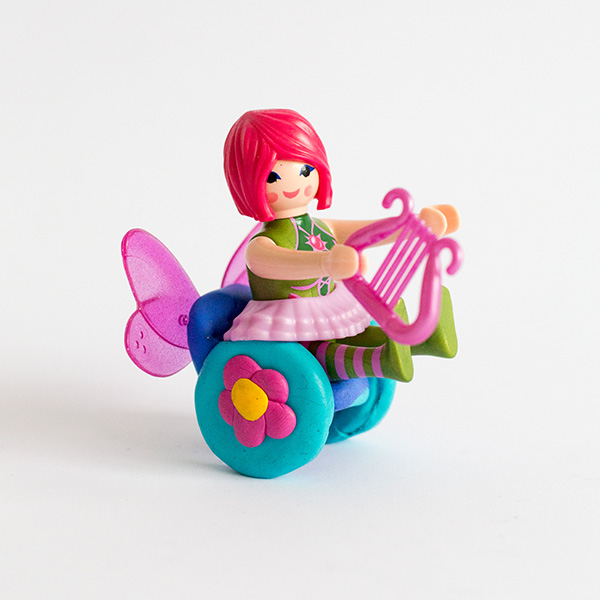 #ToyLikeMe makeover image showing a Playmobil fairy with a model wheelchair. The wheelchair has wings on the back of it.