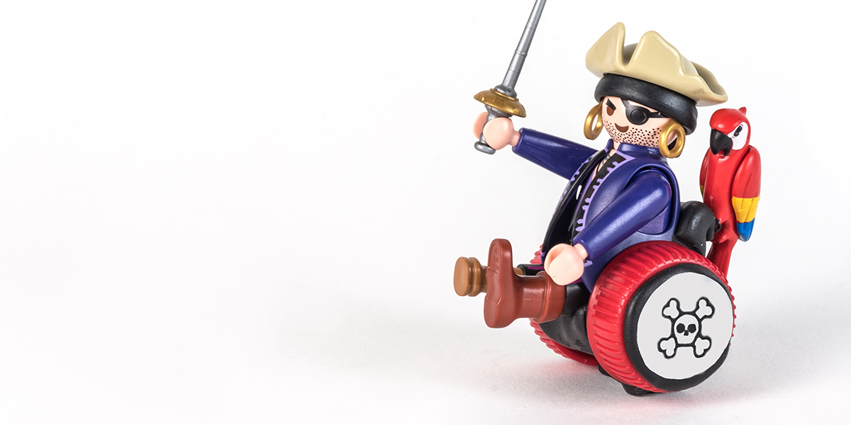 #ToyLikeMe makeover image of Playmobil pirage figure using a black and red wheelchair made of modelling clay.
