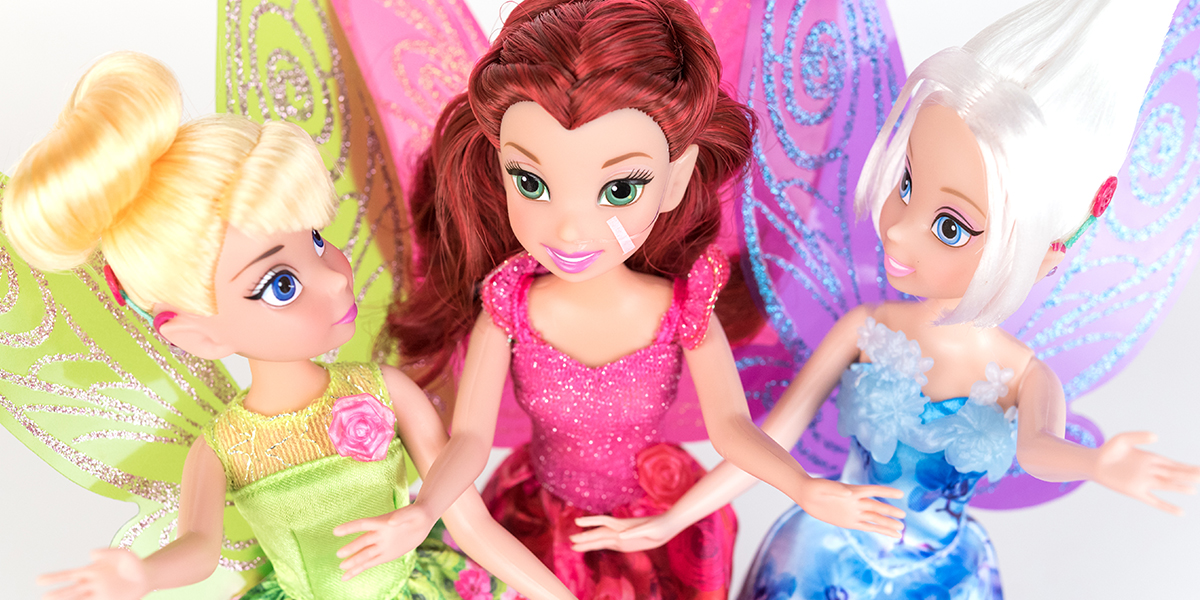 #ToyLikeMe makeover image showing Disney Tinkerbell and Periwinkle dolls with hot pink model cochlear implants chatting with Disney fairy Rosetta who has a nasal feeding tube.