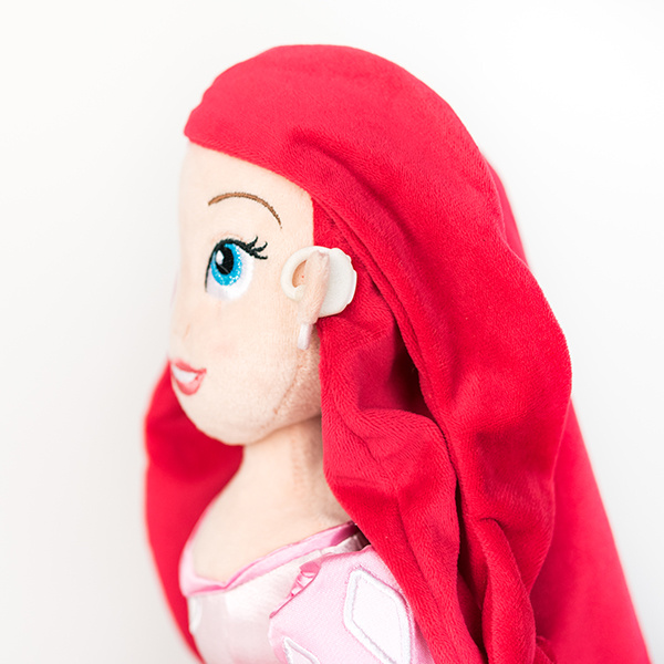 Plush Disney Arial doll with white hearing aid.