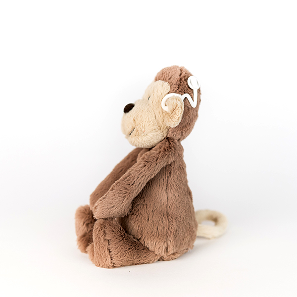 Brown plush monkey with white 3D printed cochlear implant.