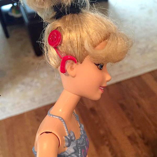 Community makeover image showing a Barbie doll with a model cochlear implant.