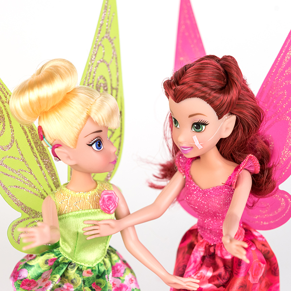 #ToyLikeMe makeover image showing Disney Tinkerbell doll with a hot pink model cochlear implant chatting with Disney fairy Rosetta who has a nasal feeding tube.