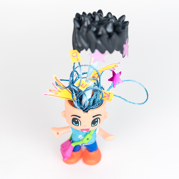 #ToyLikeMe makeover Image of Pinypon doll with dyslexia. The hair of the doll is floating to reveal the contents of the mind - stars, sparkle and brilliance, alongside a few back to front letters.